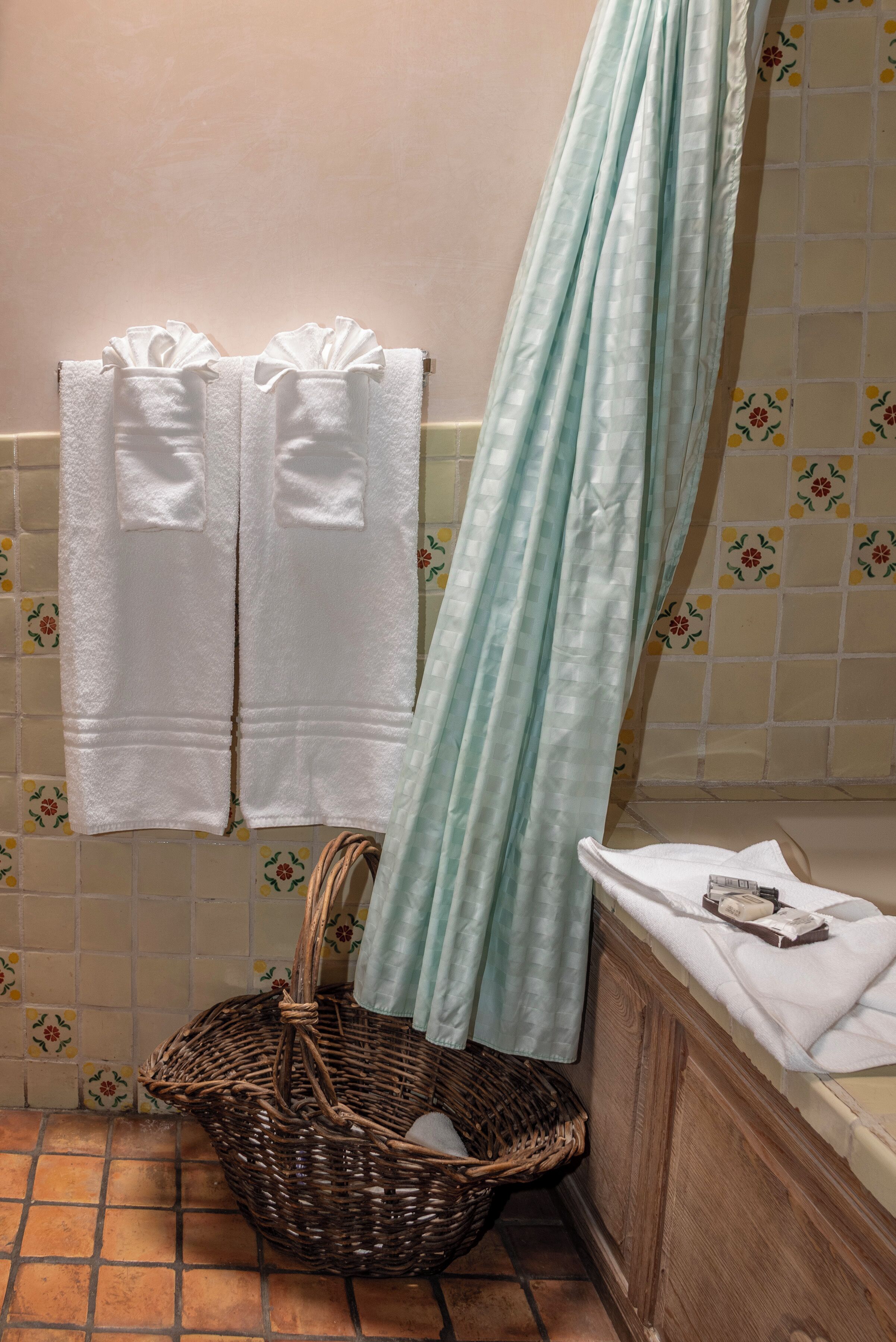 A bathroom with two white towels hanging on a rack, a wicker basket, and a shower curtain.