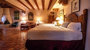 Une chambre spacieuse avec un grand lit, des poutres apparentes, un sol carrelé et une cheminée.