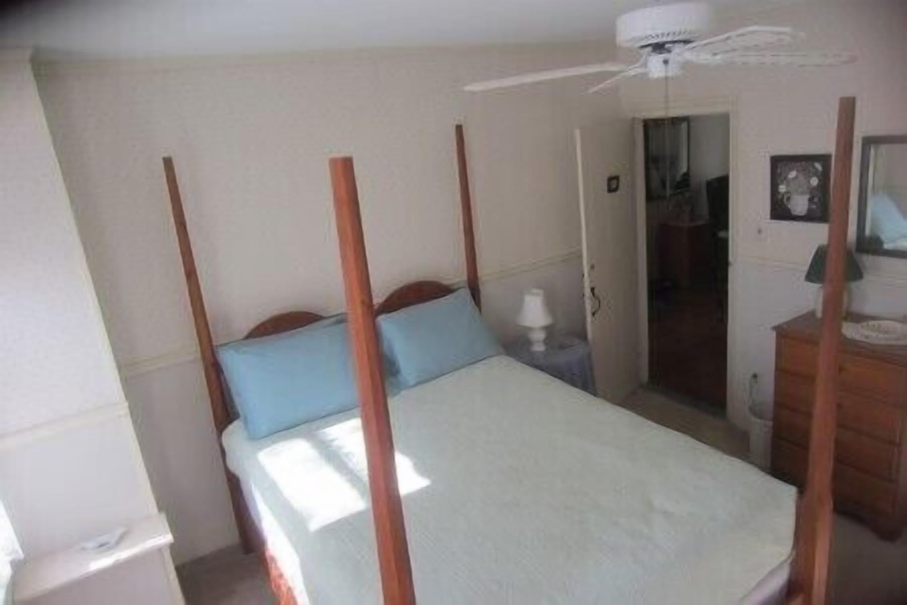 A bedroom with a bed, a nightstand, a dresser, and a ceiling fan.