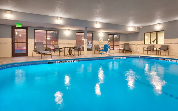 An indoor swimming pool with lounge chairs and a no diving sign.