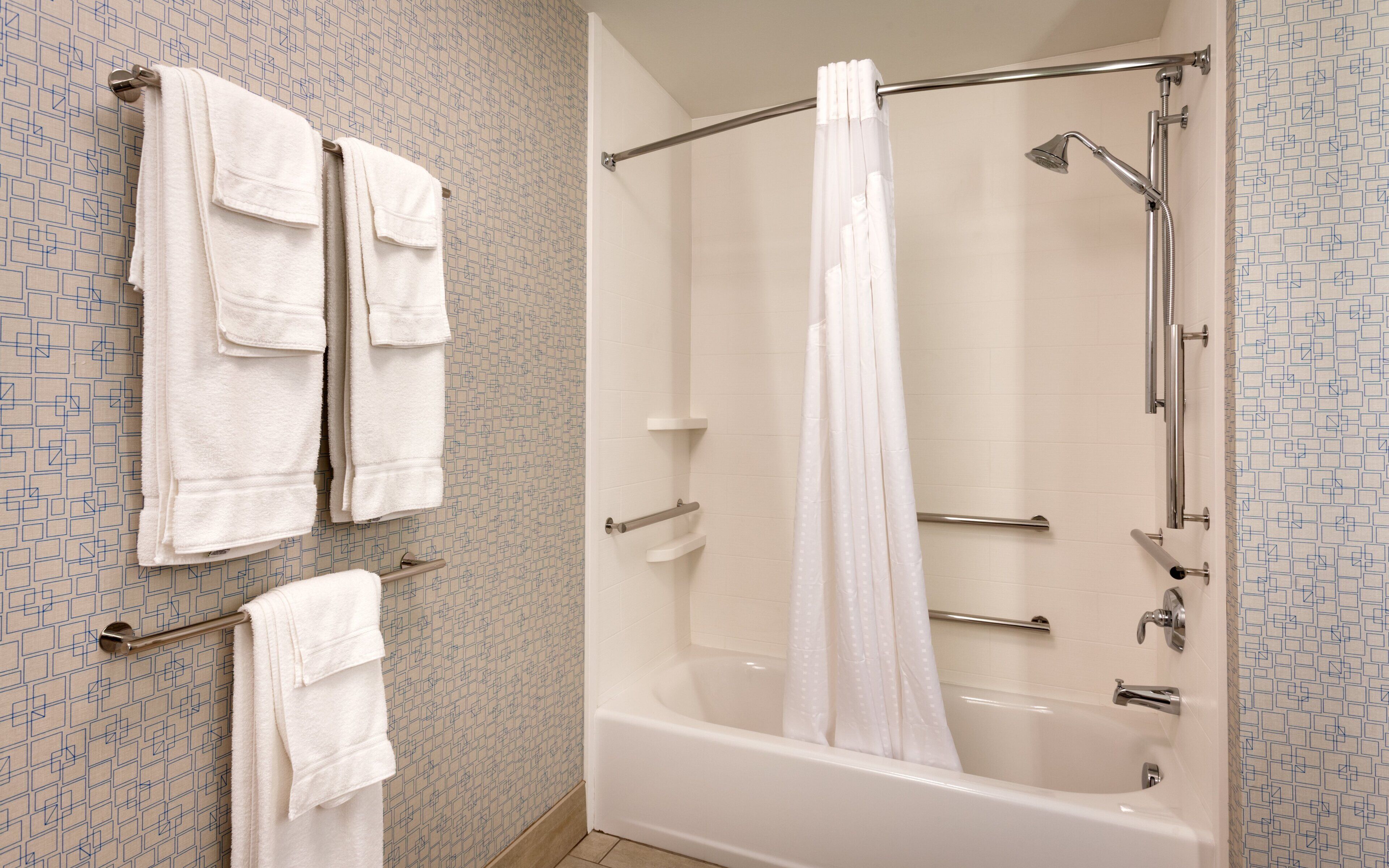 A bathroom with a bathtub, shower, and two towel racks with towels.