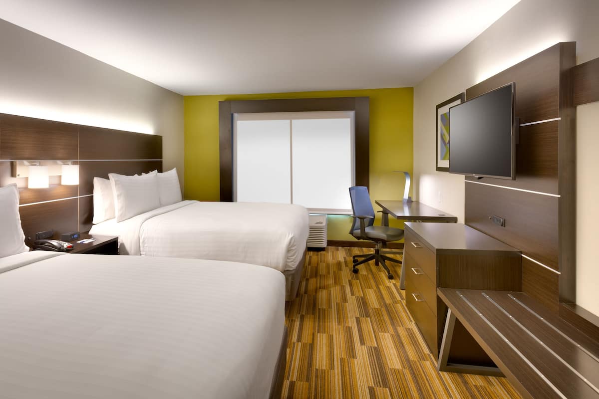 Une chambre d’hôtel avec deux lits, un bureau, une chaise, une télévision et une grande fenêtre.