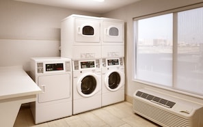A laundry room with stacked washers and dryers, a table, and a large window. - Holiday Inn Express Hotel & Suites El Paso I-10 East by IHG (El Paso)
