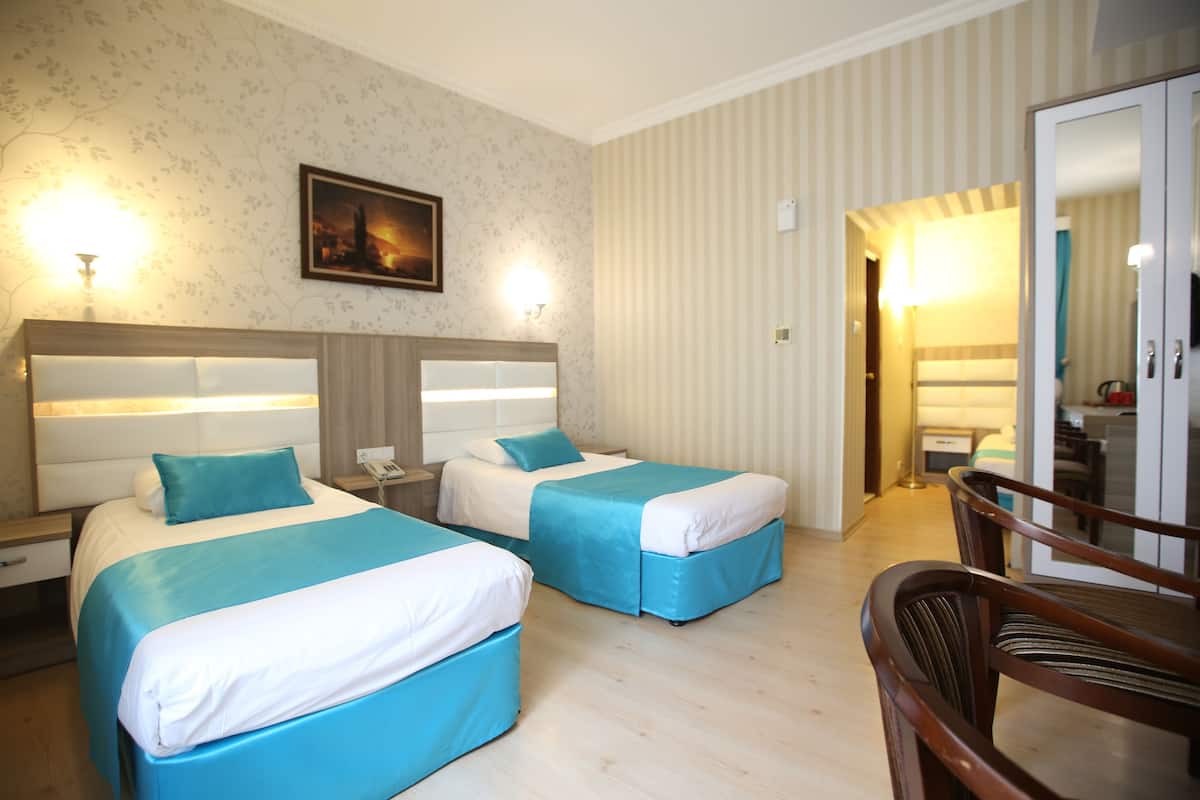 Ein Hotelzimmer mit zwei Betten, einem Holzkopfteil, einem Nachttisch, einem Sessel und einem Bild an der Wand.