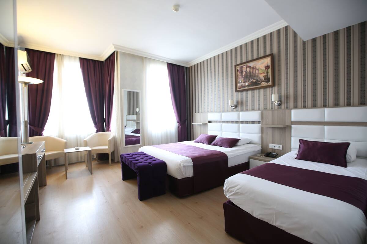 Ein Hotelzimmer mit zwei Betten, einem Schreibtisch und einem Stuhl.