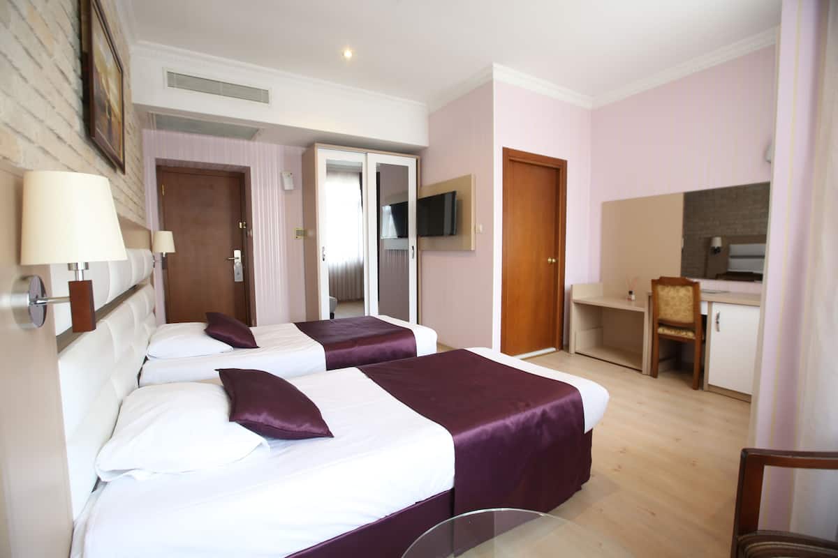 Ein Hotelzimmer mit zwei Betten, einem Fernseher, einem Schreibtisch und einem Stuhl.