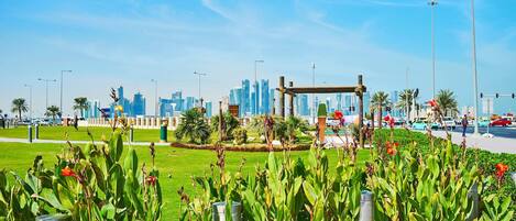 A park with a metal sculpture, green grass, and a city skyline in the background.