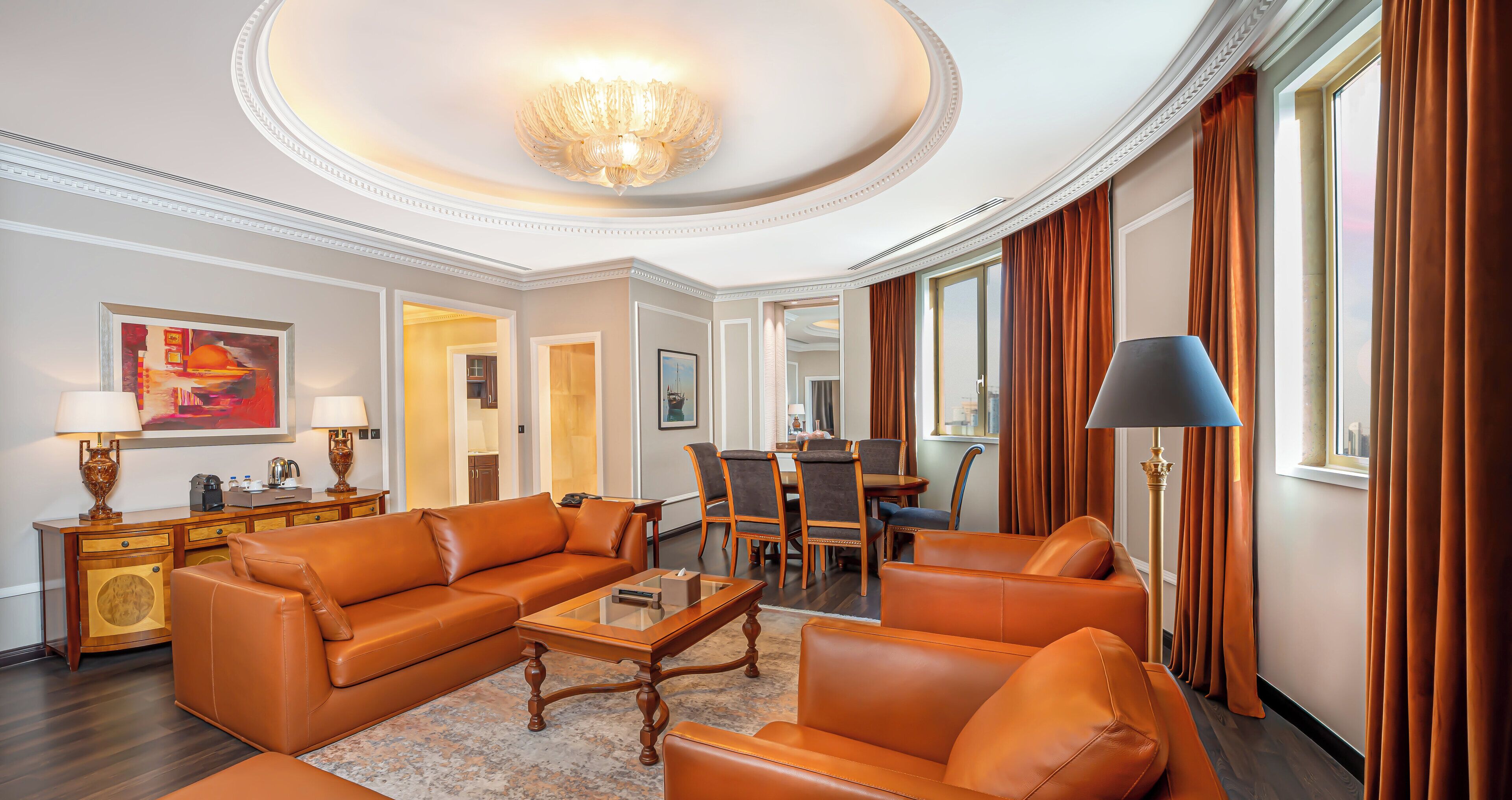 Ein geräumiges Wohnzimmer mit Ledersofas, einem Glastisch und einer Kristallleuchtre.