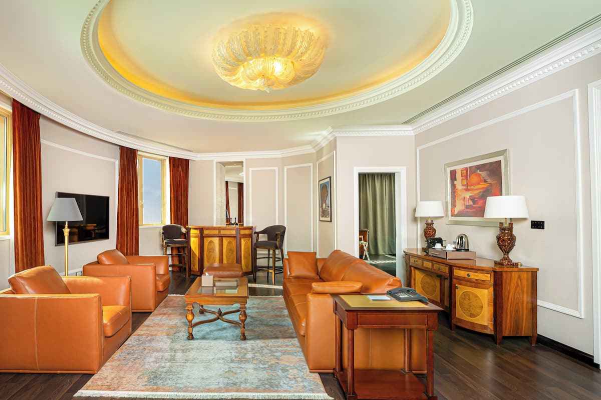 A spacious living room with leather sofas, a wooden coffee table, and a chandelier.