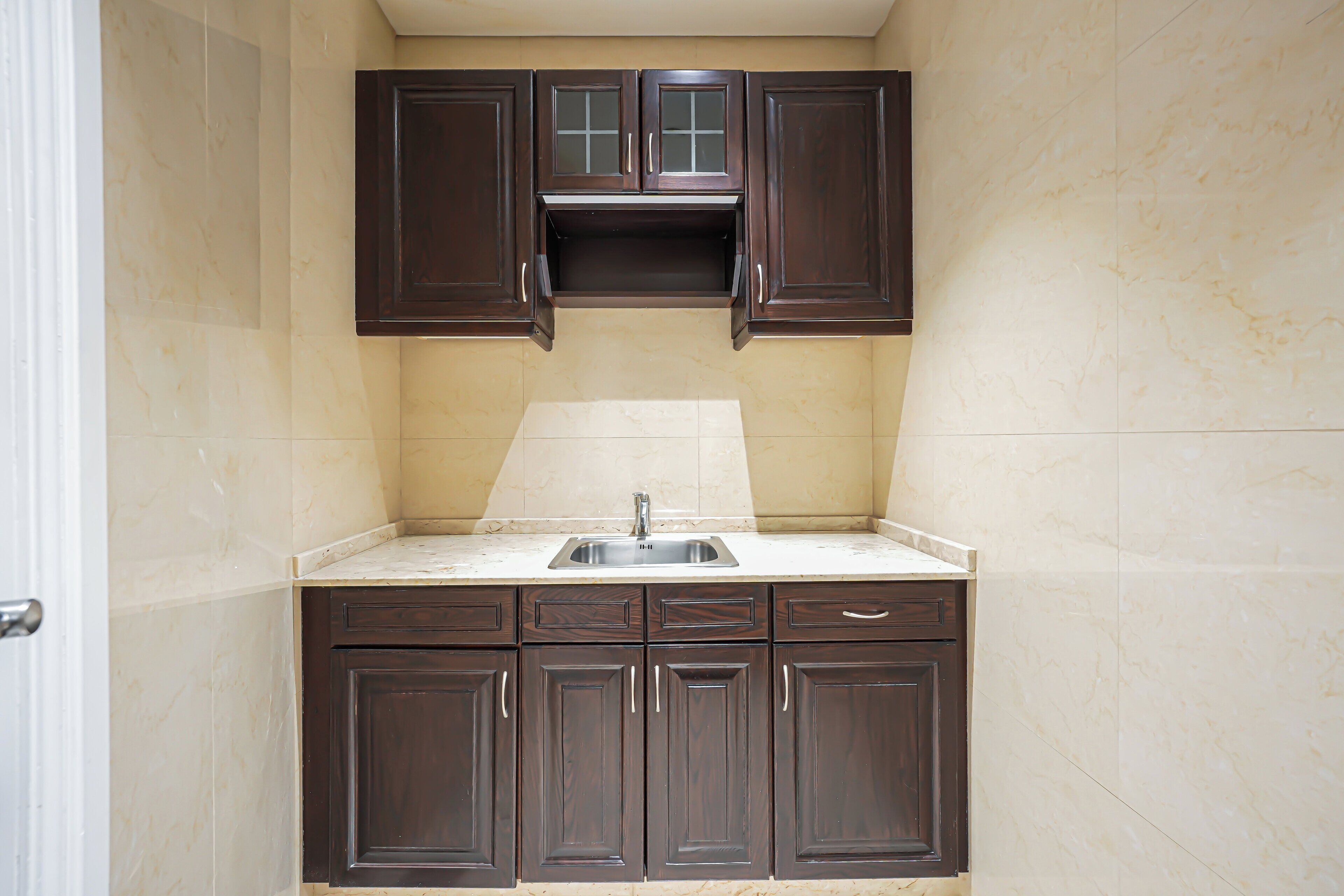 A kitchen with dark brown cabinets, a white countertop, and a sink.