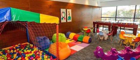 Zona infantil con piscina de pelotas, fosa de espuma y estructuras de juego coloridas.