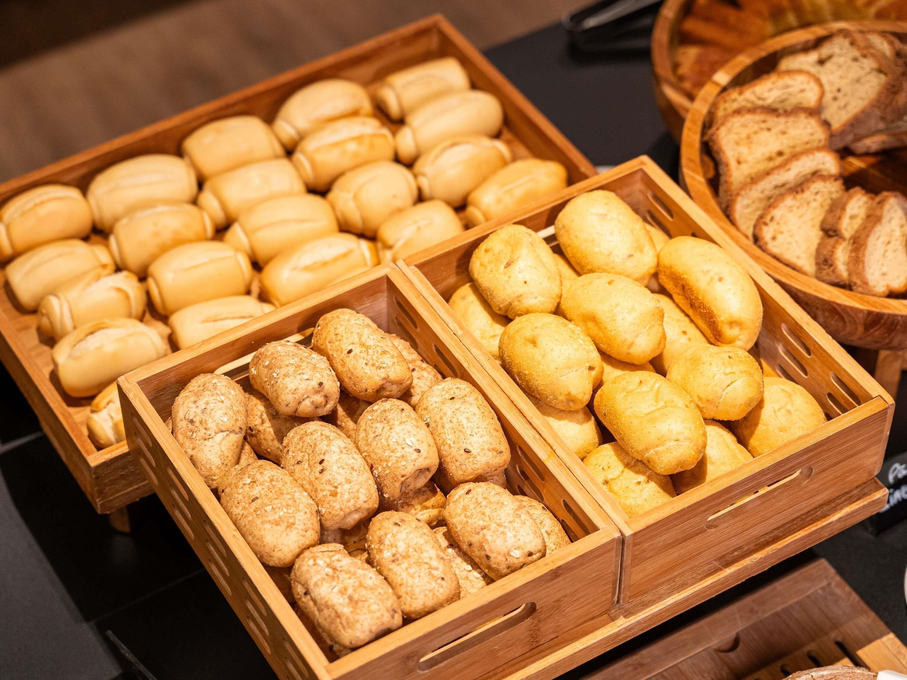 Un bufé con diversas opciones de panadería, incluyendo pan, bollos y pasteles.