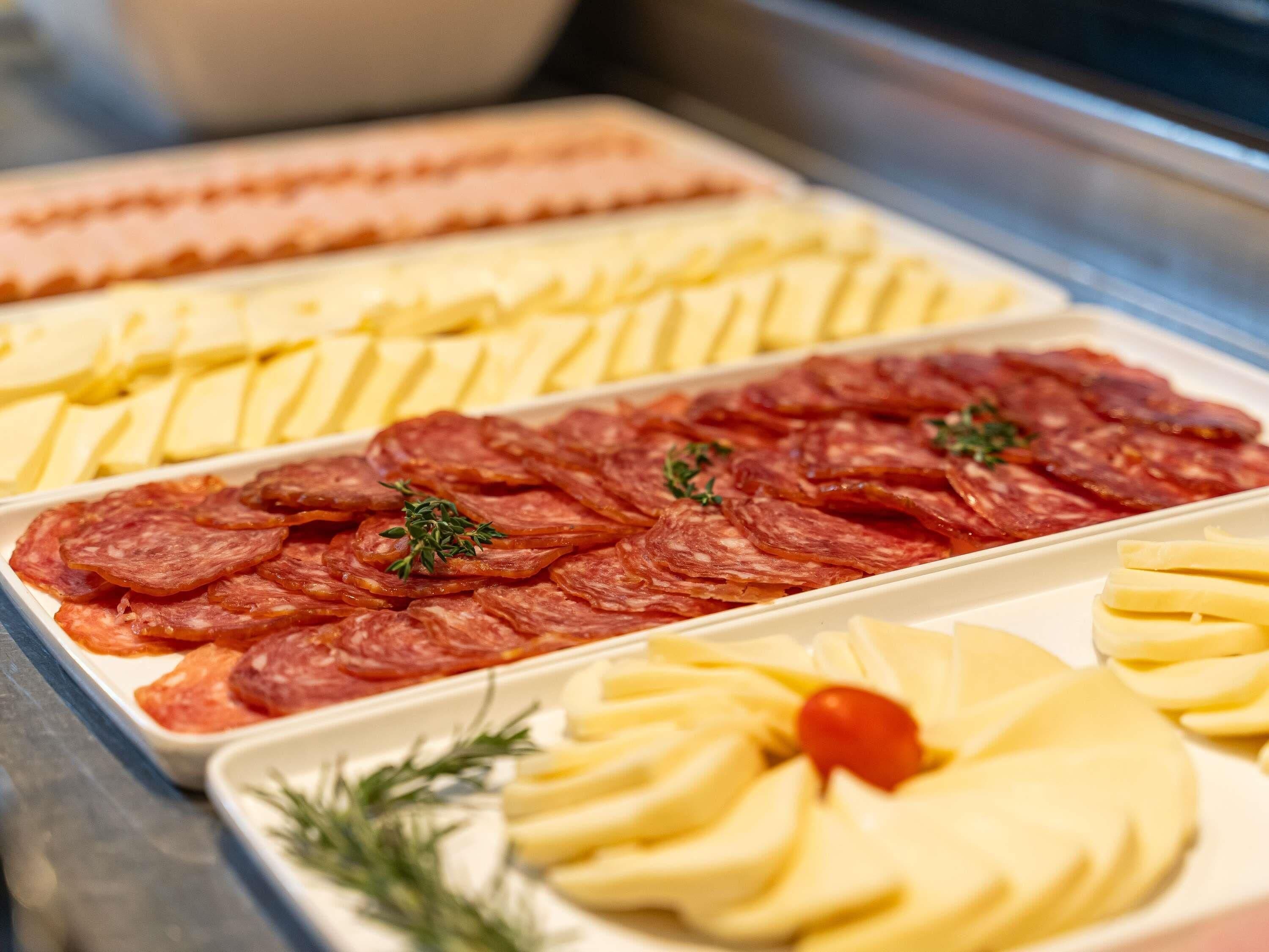 A buffet with various food items including sliced meats, cheeses, and garnishes.