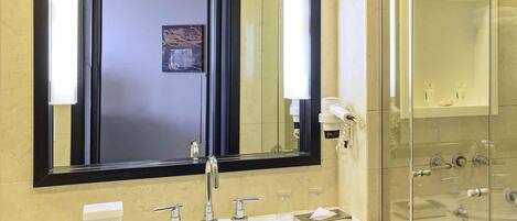 Un baño con un espejo grande, un lavabo, cabina de ducha de vidrio y un perchero para toallas.