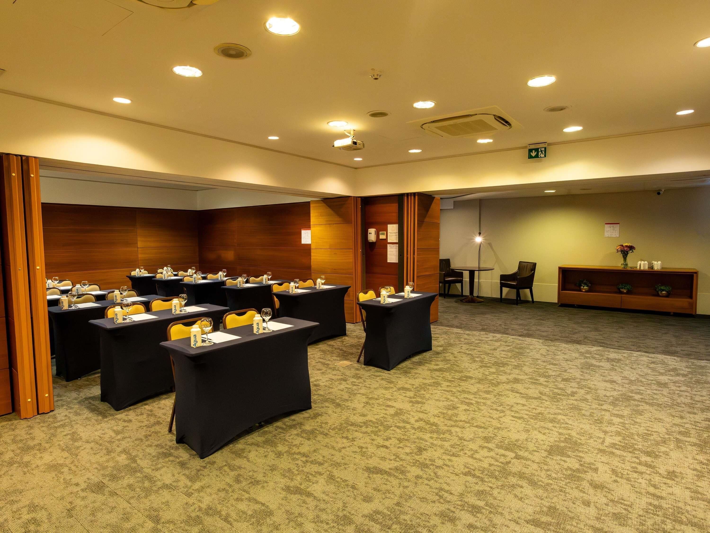 Une salle de conférence équipée de tables, de chaises et d’un espace d’accueil.