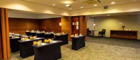 A conference room with tables, chairs, and a reception area.