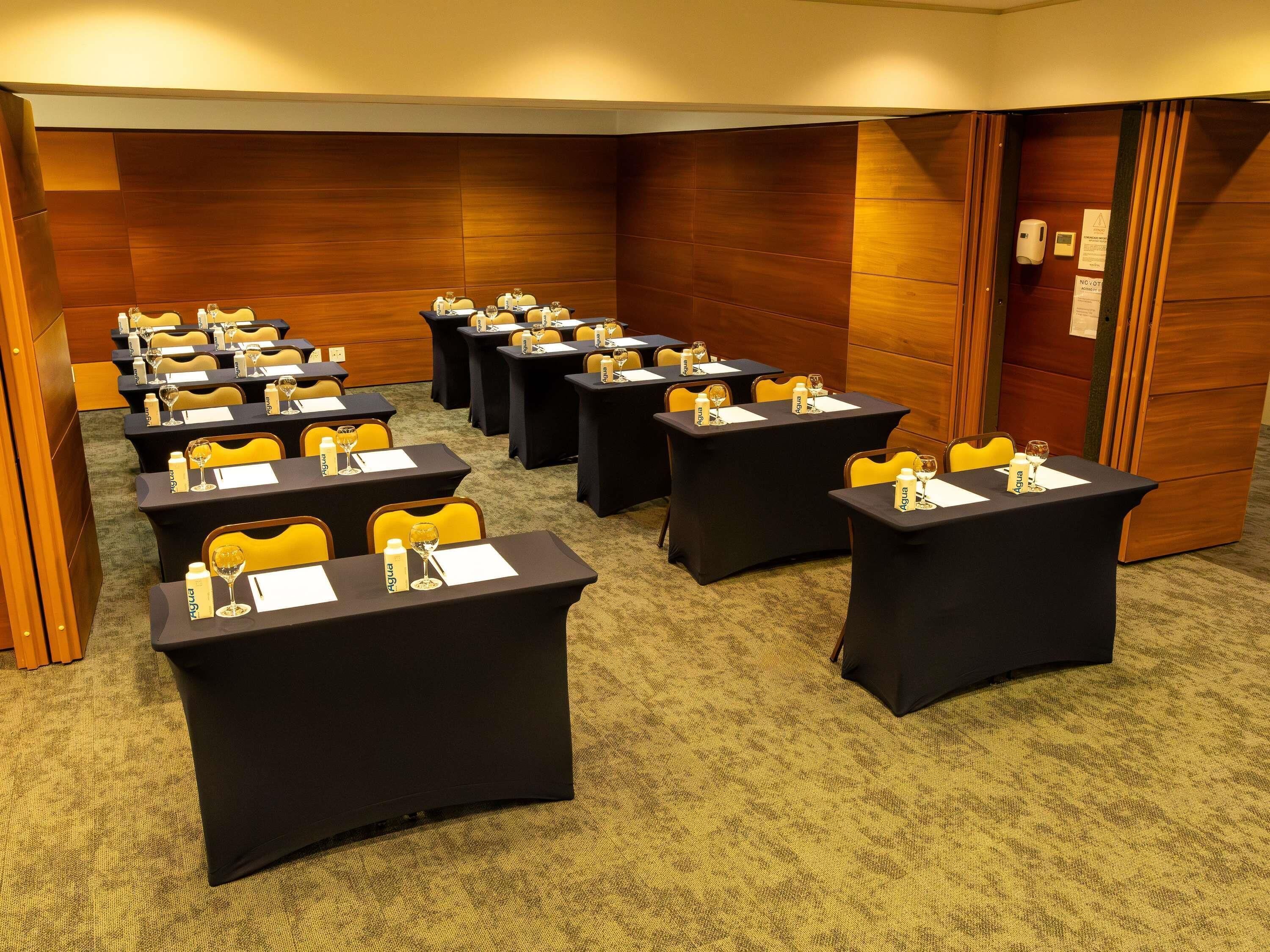 A conference room with multiple tables, chairs, and water bottles.