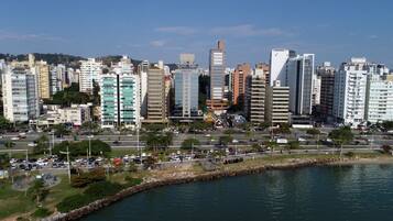 A cityscape with modern high-rise buildings, a waterfront promenade, and a clear sky.