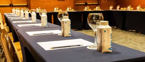 A conference room with long tables, nameplates, water bottles, and glasses.