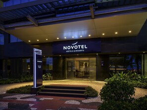 A hotel entrance with a sign reading 'NOVOTEL HOTELS & RESORTS,' a well-lit entrance, and a paved pathway leading to the door. - Novotel Florianópolis (Florianópolis)