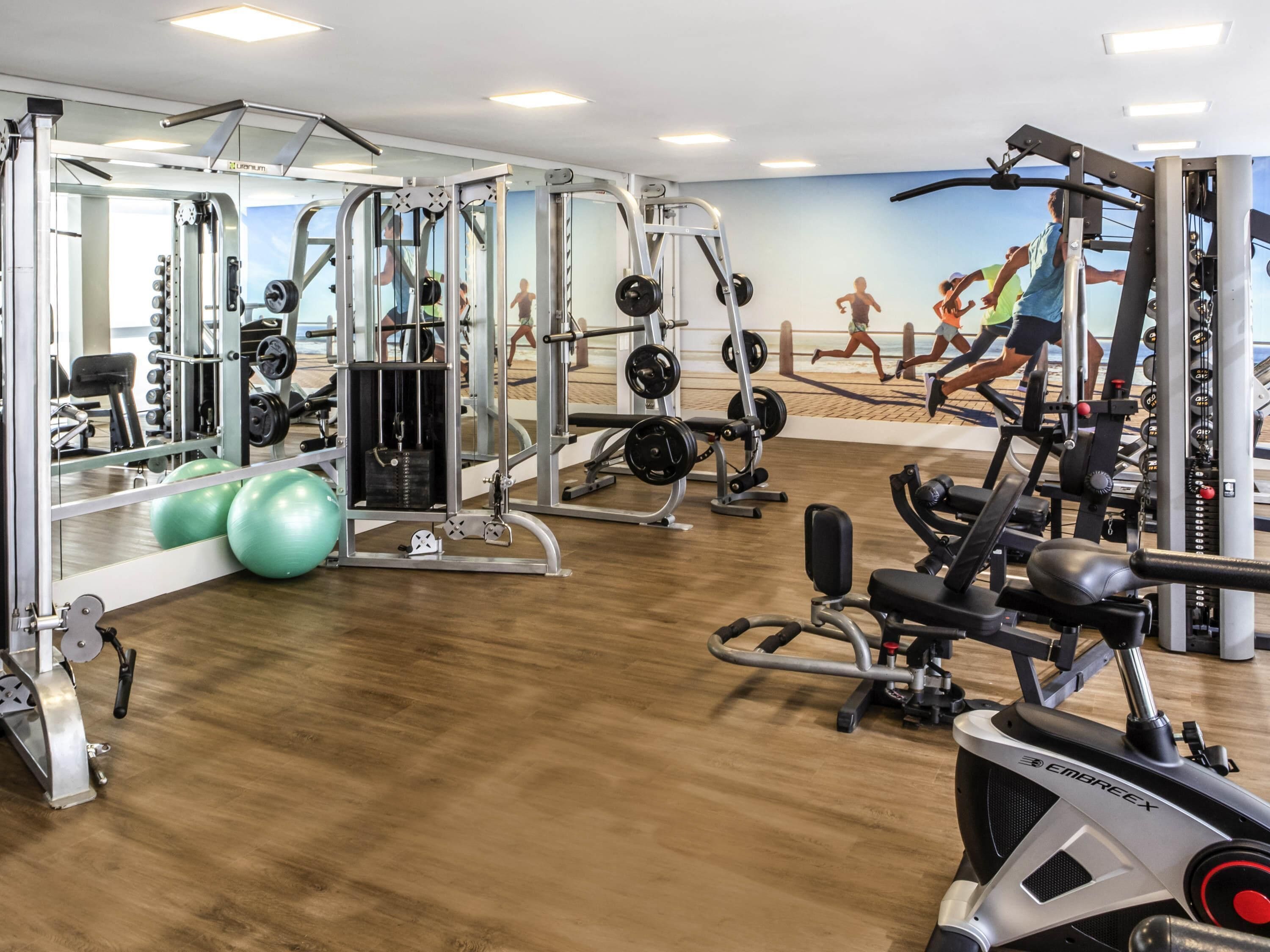 Un gimnasio con equipo cardiovascular, máquinas de pesas y pesas sueltas.