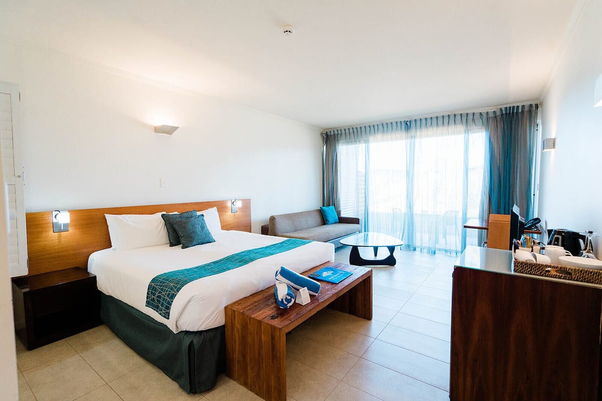 Een hotelkamer met een bed, een bank, een bijzettafeltje, een bureau en uitzicht op het groen.