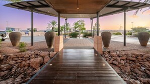 A covered walkway leading to a pool area with large planters and a view of the surrounding landscape.