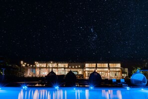 A modern hotel with a pool, starry night sky, and illuminated structures. - Mantarays Ningaloo Beach Resort (Exmouth)