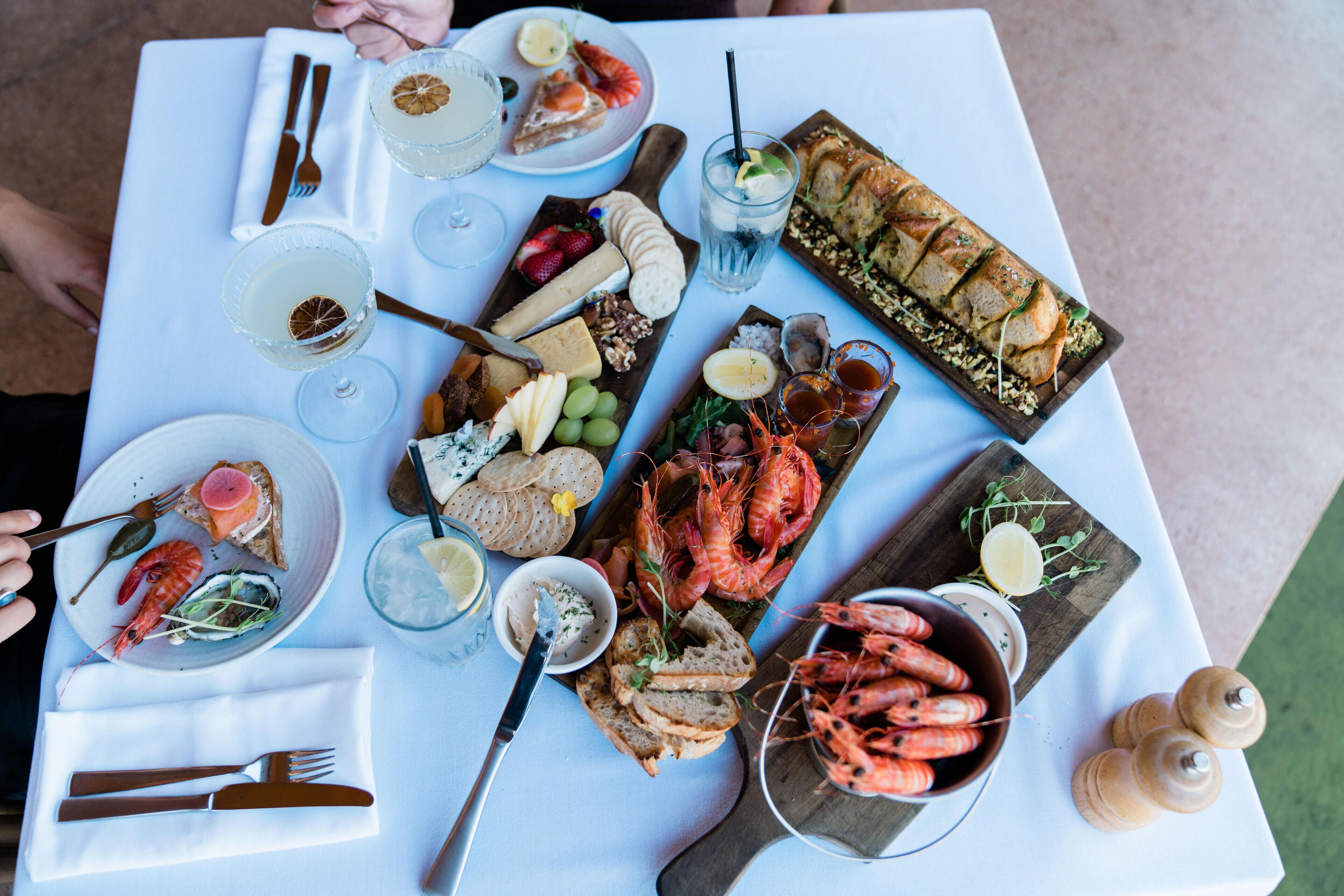 Une table dressée avec divers aliments, notamment des fruits de mer, du pain et des boissons.