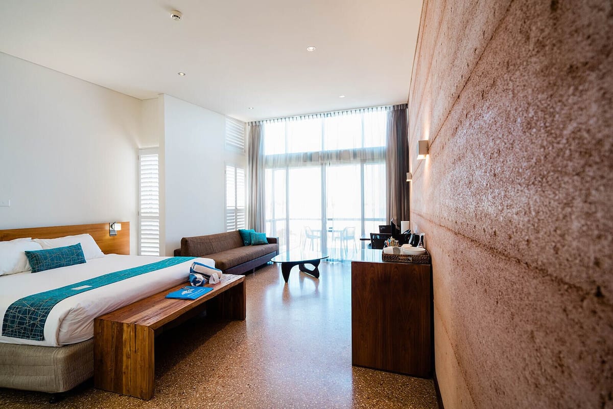 Een hotelkamer met een bed, een bank, een bureau en een groot raam.
