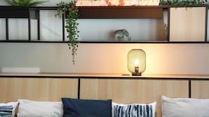 Una sala de estar moderna con un sofá, plantas decorativas, un letrero de neón y un estante de pared con una pequeña figurita de elefante.