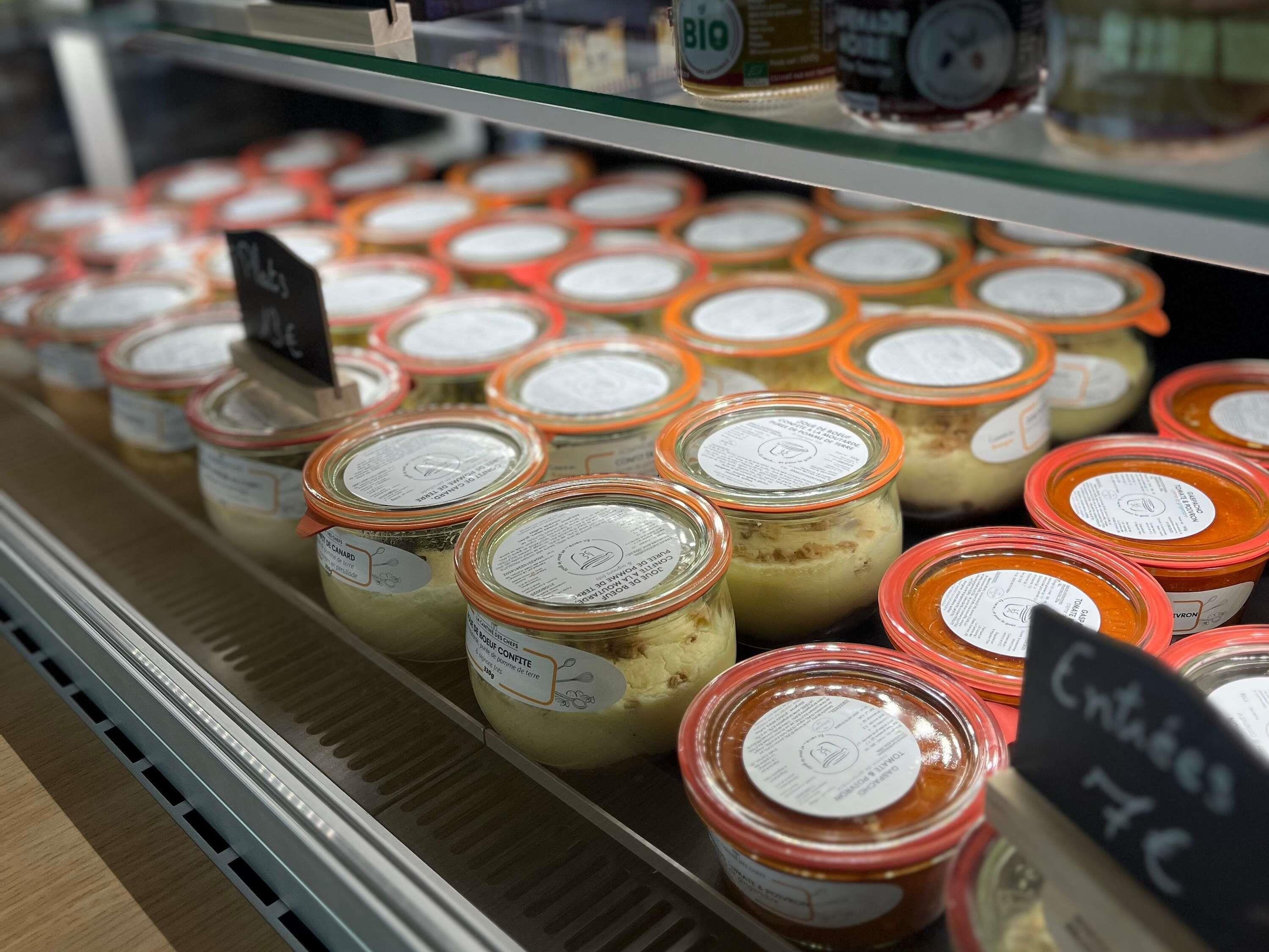 Vitrine refrigerada com potes de produtos alimentícios, alguns com preços indicados.