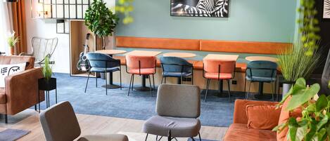A modern lounge area with seating arrangements, a wall-mounted artwork, and a guitar.