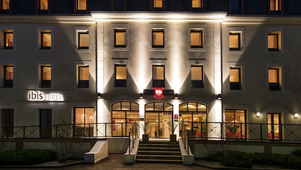 Una entrada de hotel con un letrero que dice 'ibis HOTEL' y una escalera que conduce a la entrada.