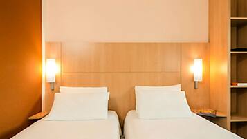 Ein Hotelzimmer mit zwei Betten, einem Holzkopfteil und Wandleuchten.