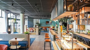 Un café moderno con zona de bar, asientos y una exhibición de pasteles.