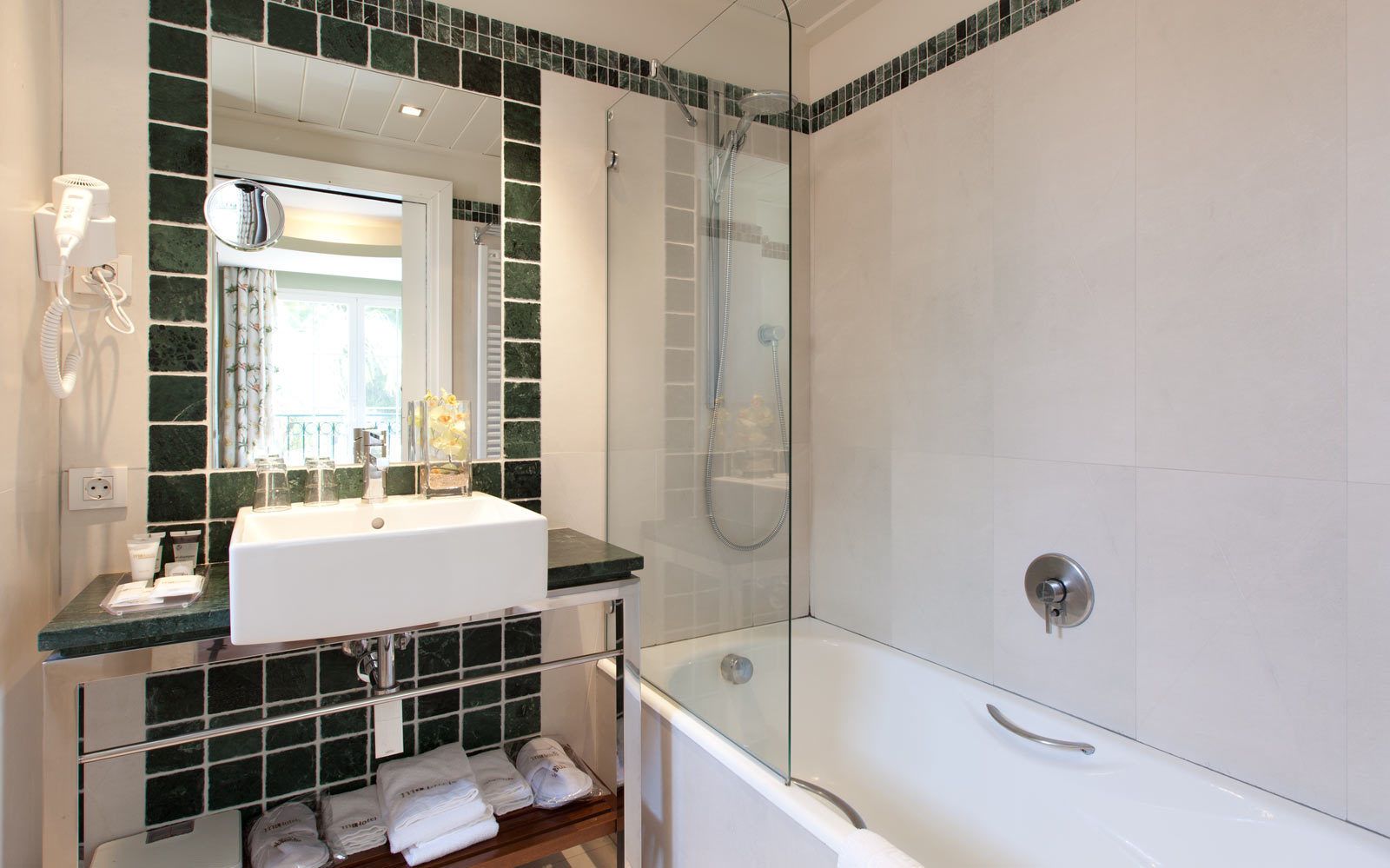 A modern bathroom with a glass-enclosed shower, a white sink with a marble countertop, and a mirror above the sink.
