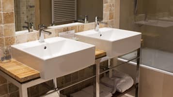 A bathroom with two sinks, a mirror, a shower, and a towel rack.