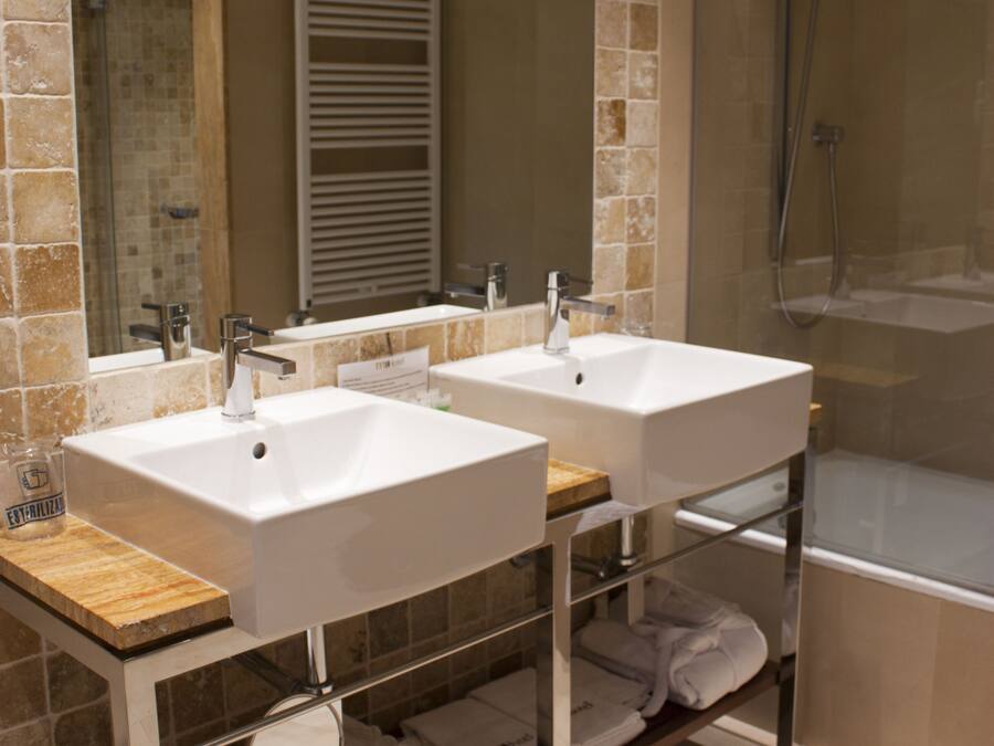 A bathroom with two sinks, a mirror, a shower, and a towel rack.
