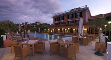 A rooftop pool area with outdoor seating and a building in the background.