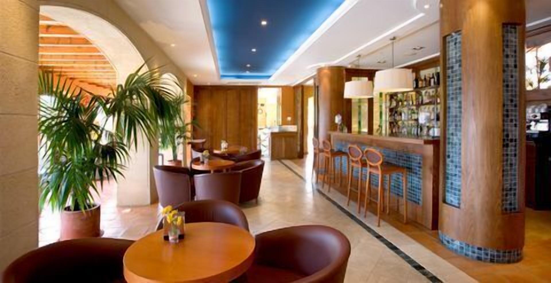 Eine Hotelhalle mit Barbereich, Sitzgelegenheiten und Topfpflanzen.