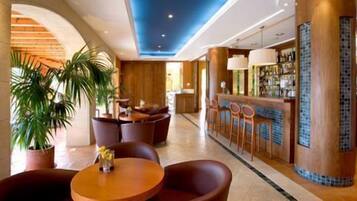A hotel lobby with a bar area, seating arrangements, and potted plants.