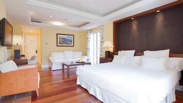 Una habitación de hotel con una cama grande, un sofá, una mesita con artículos para el desayuno y un televisor.