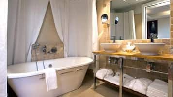Un baño moderno con una bañera independiente, un tocador con un espejo grande y un perchero para toallas.