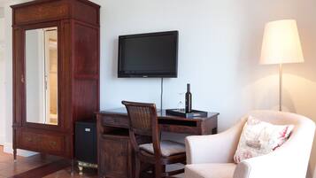 A room with a wooden cabinet, a desk with a chair, a television, and a lamp.