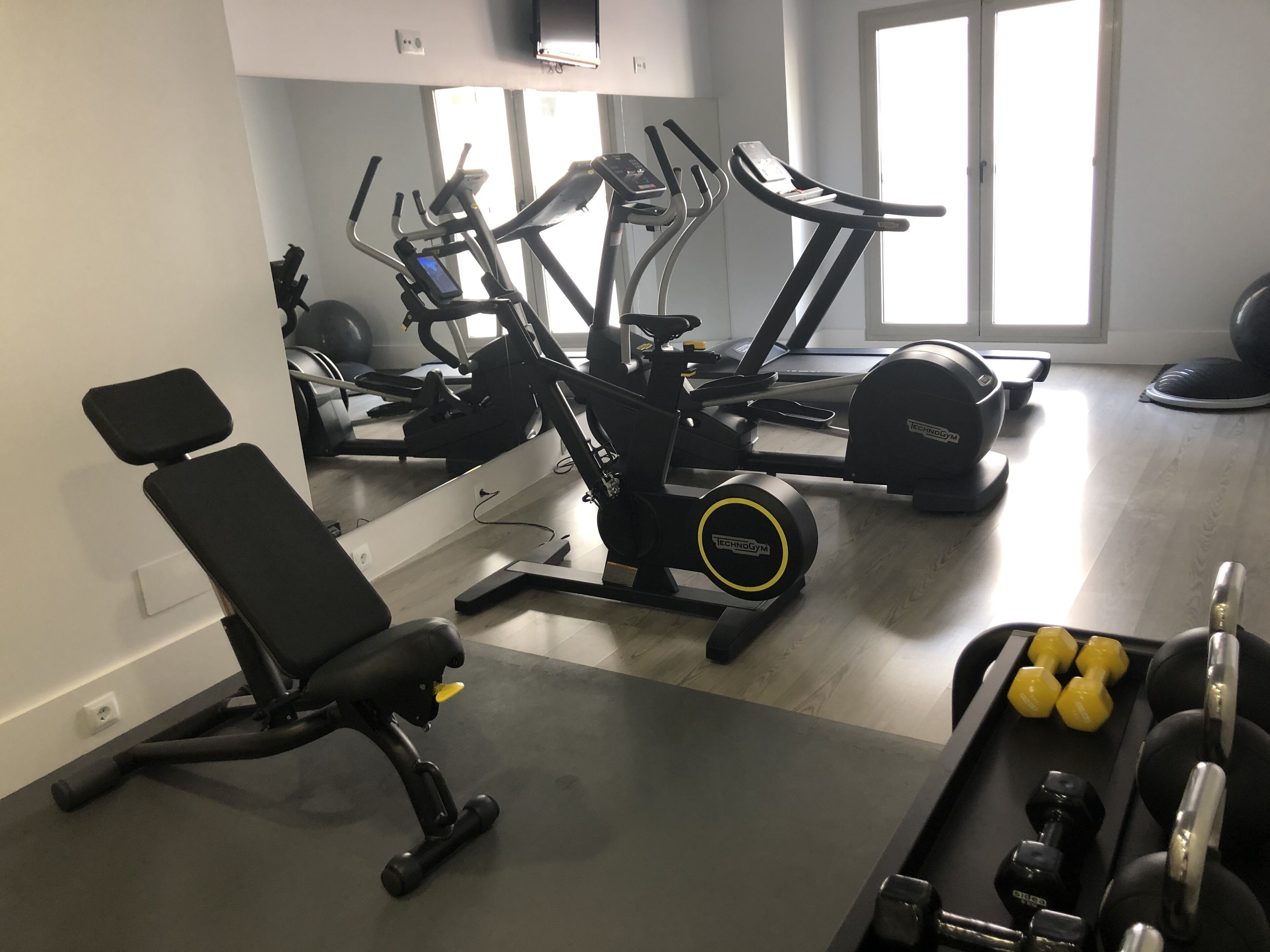 Un gimnasio con equipo de ejercicio que incluye una cinta de correr, elíptica y pesas.