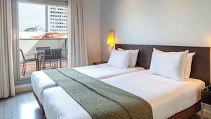 A hotel room with two beds, a balcony with a table and chairs, and a city view. - Suites Viena Plaza de España (Madrid)