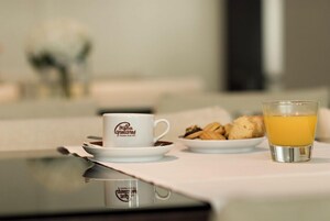 A breakfast setting with a cup labeled "Willa Capellanes," a plate of cookies, and a glass of orange juice on a table.