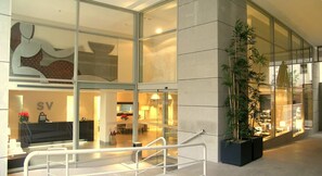 Un moderno vestíbulo de hotel con paredes de vidrio, una recepción y una gran planta en maceta.