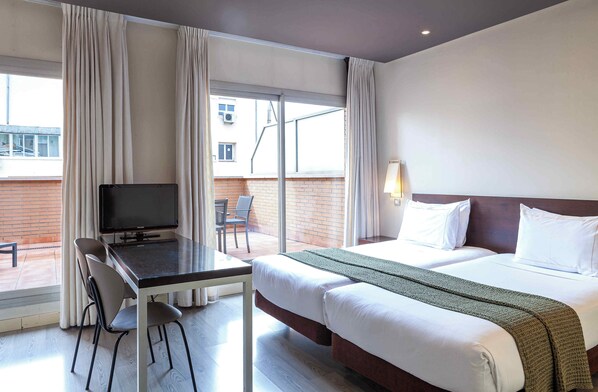 Habitación de hotel con cama, escritorio y televisión, y vista al exterior.